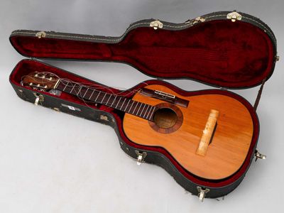 une guitare dans un étui, posée sur une surface blanche
