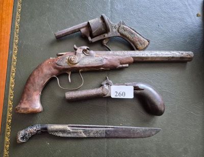 trois vieux pistolets et un couteau posés sur une table, avec une étiquette de prix