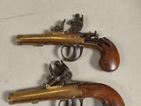 two antique pistols with wooden grips on a white surface