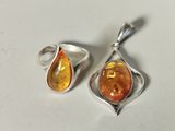 two pieces of silver and amber jewelry sitting on a white surface