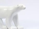 a small white polar bear statue on a white surface