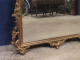 a large mirror sitting on the floor in front of a blue wall
