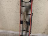 un snowboard appuyé contre un mur, auquel est fixé un autre snowboard