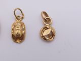 three pieces of gold jewelry sitting on top of a white surface