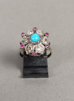 un gros plan d'une bague ornée d'une turquoise entourée de pierres roses et blanches