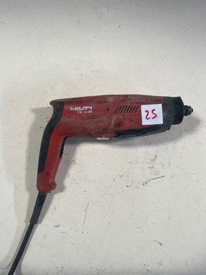 une perceuse rouge posée sur une surface blanche