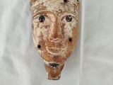 une image représentant un masque en argile posé sur un drap blanc