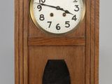 une horloge en bois avec un cadran noir sur fond gris