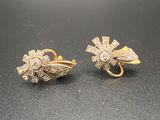 deux paires de boucles d'oreilles en or et diamants posées sur un fond noir