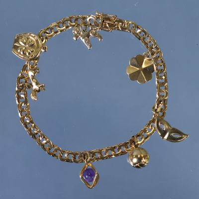 bracelet plaqué or orné de breloques, sur fond bleu