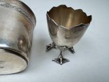 a silver cup sitting next to a silver cup on a table