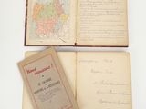 trois vieux livres sont ouverts sur une surface blanche, avec une carte en arrière-plan