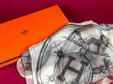 an orange box with a white scarf and a black and white scarf on a pink surface