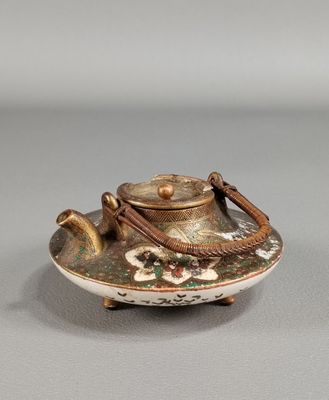 une petite théière avec une anse posée sur une table