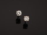 a pair of diamond earrings on a black surface