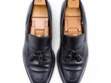 a pair of black leather shoes with tassels on them