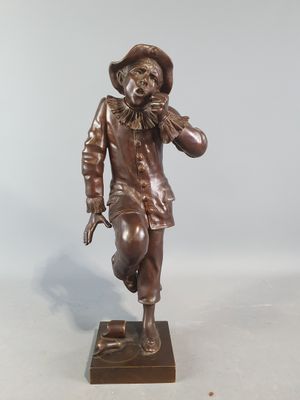 statue en bronze représentant un homme coiffé d'un chapeau et muni d'une canne, posée sur un socle en bois