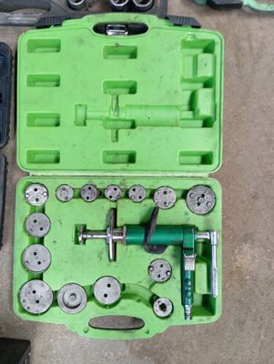 une mallette verte posée par terre, contenant des outils