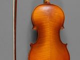 a violin with a bow and a bow rest on a gray surface