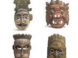 quatre masques en bois de formes et de tailles différentes sur un fond blanc