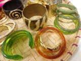 many different colored bracelets and bangles on a tray
