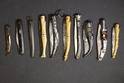 plusieurs types de couteaux sont alignés sur une surface noire