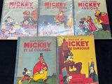 Quatre livres de Mickey Mouse sont alignés sur une surface noire
