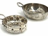 pair of silver plated bowls with handles on a white surface