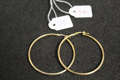 deux paires de boucles d'oreilles créoles en or posées sur une surface noire