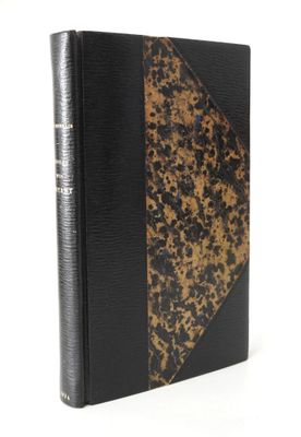 an old book with a black cover sitting on a white surface