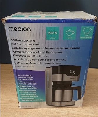 boîte contenant une cafetière posée sur une table, avec une tasse de café à côté