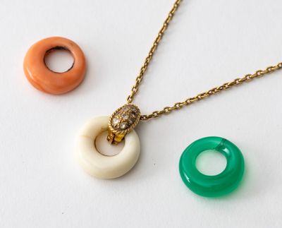 deux colliers et une bague posés sur une surface blanche