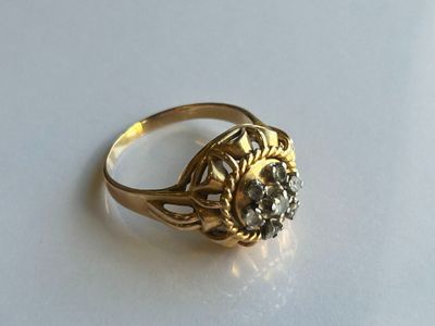 une bague en or sertie d'un diamant, posée sur un fond blanc