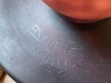 a red vase sitting on top of a black plate