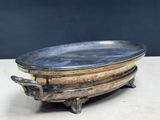 an old silver plate with a handle on a wooden table