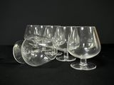 Plusieurs verres à vin vides sont alignés sur une surface noire