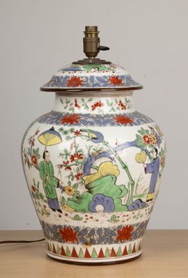 un vase avec un couvercle posé sur une table sur laquelle se trouve une lampe
