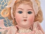 a doll that is sitting on a chair with a pink dress