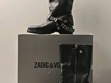 deux paires de bottes noires ornées de chaînes, posées sur une boîte