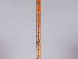 a wooden flute on a clear stand against a gray background