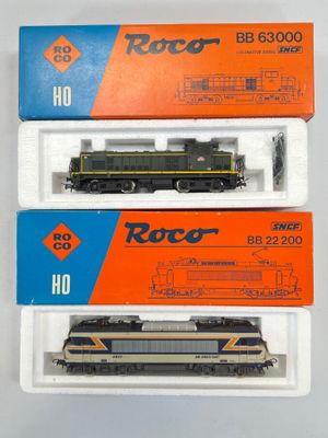 trois trains miniatures dans leurs boîtes, empilés les uns sur les autres sur une surface blanche