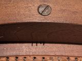 a close up of a wooden chair with a metal button on it