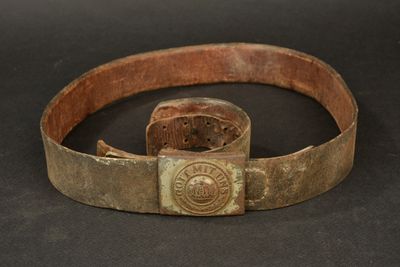 an old belt with a metal buckle on a black surface