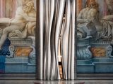 une photo d'une sculpture dans une pièce, avec un tableau accroché au mur derrière elle