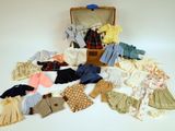 une valise remplie de vêtements et des vêtements posés sur une surface blanche