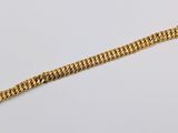 a close up of a gold chain bracelet on a white surface