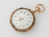 une montre de poche en or avec un cadran blanc sur une surface blanche