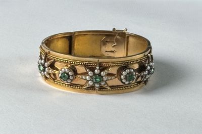 a close up of a gold bracelet on a white surface