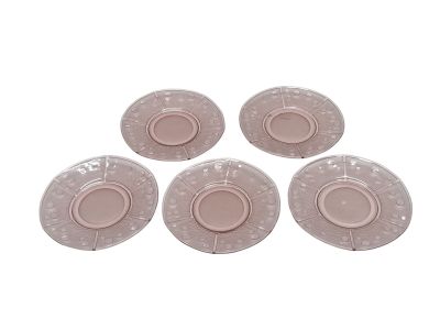 quatre assiettes en plastique roses percées de trous, posées sur une surface blanche