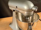 a silver mixer on a wooden table with a black background